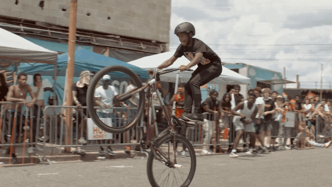 Crash Boys rider performing a wheelie in front of the community